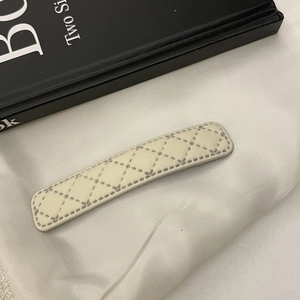 Détail de la pince à cheveux en similicuir crème avec surpiqûres à motif de losanges