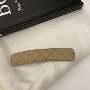 Détail de la pince à cheveux en similicuir kaki avec texture élégante à losanges
