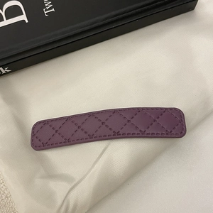 Détail de la pince à cheveux en similicuir violet foncé avec texture matelassée et couture