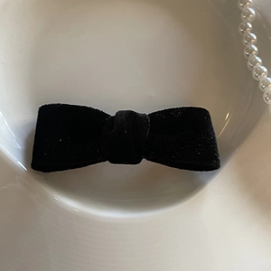 Dettaglio di un fermaglio per capelli in velluto nero su un piatto di porcellana bianca
