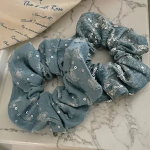 Lot de 2 chouchous en denim avec paillettes argentées sur fond de marbre blanc