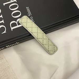 Détail d'une pince à cheveux en similicuir vert clair avec surpiqûres losanges