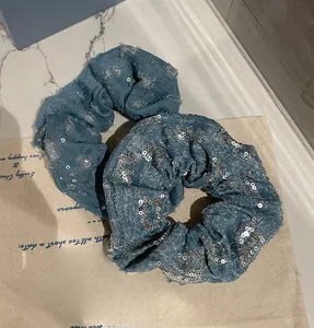 Détail des chouchous en jean avec paillettes argentées et bords effilochés pour cheveux