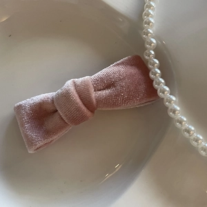 Fermaglio per capelli con fiocco in velluto rosa su piatto di ceramica bianca
