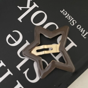 Pince à cheveux étoile marron avec fini brillant et boucle dorée sur un livre