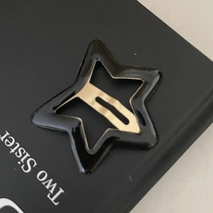 Barrette en forme d'étoile en résine noire avec clip en métal doré sur carte