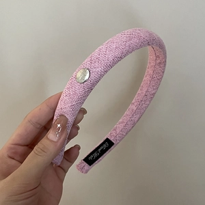 Serre-tête tressé rose avec texture granulée et petit médaillon métallique argenté