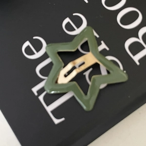 Détail d'une pince à cheveux en forme d'étoile vert olive avec finition laquée