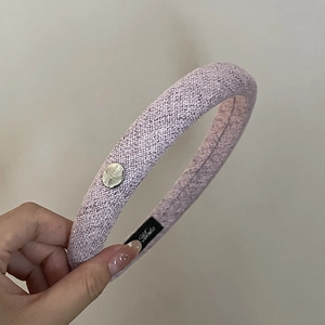 Détail d'un serre-tête tressé lilas rembourré avec badge en métal 'Believe In Yourself' argenté