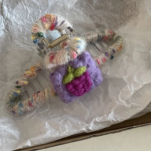 Detail of handmade strawberry wool felt hair claw clip with colorful yarn wrapping