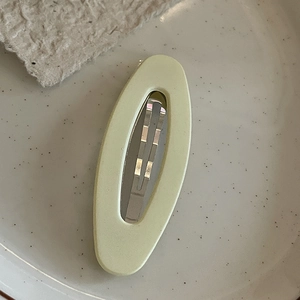 Matte light green oval BB hair clip on a white ceramic plate for sleek styling