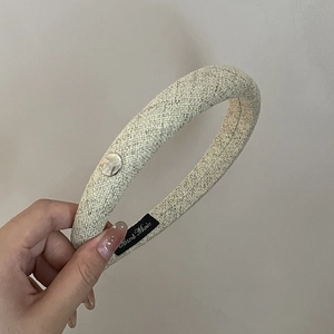 Détail de l'étiquette Hand Made sur serre-tête en lin beige avec bouton métallique