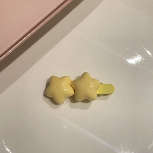 Dettaglio del fermaglio per capelli a doppia stella gialla con finitura in resina lucida