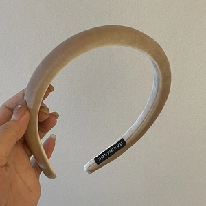 Serre-tête en velours rembourré fait main beige clair présenté dans une main