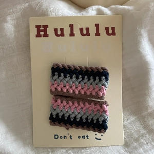 Pair of colorful crochet knit hair clips with retro stripes on a display card