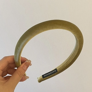 Détail du serre-tête en velours vert olive clair montrant l'étiquette et la texture