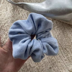 Close-up of light blue towel fabric scrunchie showing fluffy texture and elastic detail