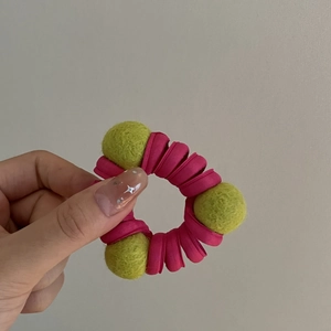 Dettaglio di elastico increspato rosa con sfere decorative in feltro di lana verde lime