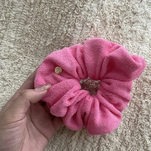 Close-up of pink towel fabric scrunchie featuring a handmade gold metal charm detail