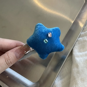 Gros plan sur la barrette étoile en velours bleu avec strass roses et verts