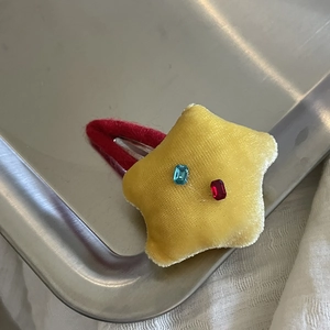 Détail macro d'une pince à cheveux étoile en peluche jaune avec des cristaux