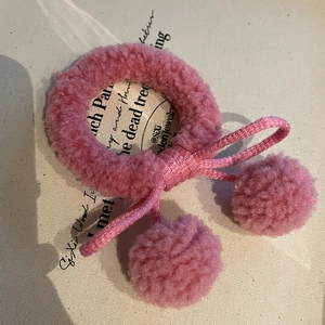 Dettaglio dell'elastico per capelli rosa in lana d'agnello con palline di peluche