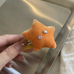 Détail de la pince à cheveux étoile en velours orange avec strass violets brillants