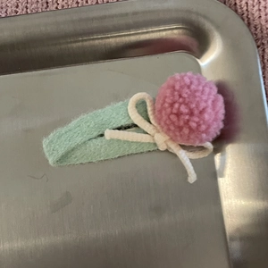 Detalle de pinza de fieltro verde menta con pompón rosa y decoración de lazo color crema