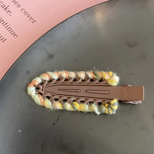 Dettaglio del fermaglio per capelli in lana intrecciata a contrasto con trama multicolore