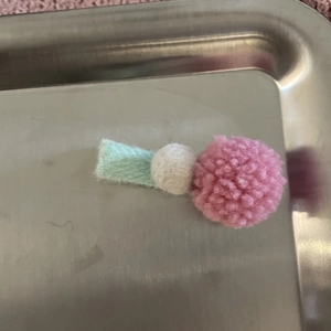 Primer plano de pompones de felpa rosas y blancos en pinza de pelo de fieltro azul