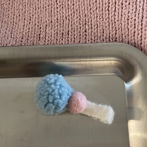 Detalle de bolas de lana de cordero en una pinza para el pelo de fieltro crema para niñas