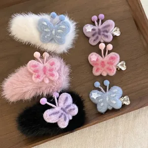 Set di sei fermagli per capelli a farfalla in peluche di vari colori su un vassoio di legno