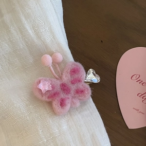 Dettaglio di un fermaglio per capelli a farfalla in feltro rosa con strass e cuore