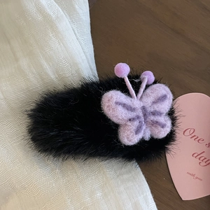 Dettaglio del fermaglio per capelli a farfalla in peluche nero con inserti in feltro