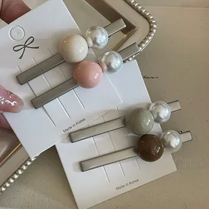 Détail de quatre barrettes à cheveux avec perles mates sur une carte de support