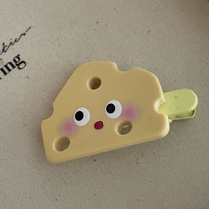 Gros plan sur la pince à cheveux mignonne en forme de fromage avec visage de dessin animé
