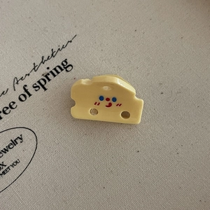 Vue détaillée d'une pince à cheveux en forme de fromage avec un visage de dessin animé mignon