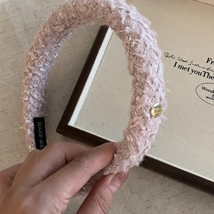 Detail of pink tweed headband featuring gold metal button and Hand Made label
