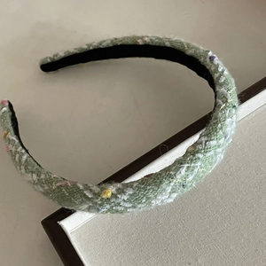 Retro green tweed headband with colorful texture on elegant beige display case