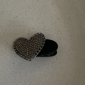 Détail d'une pince à cheveux vintage en forme de cœur avec strass sombres sur base noire