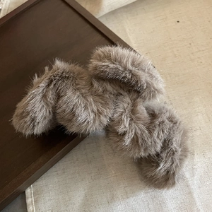 Close-up of fluffy brown faux fur hair tie with plush texture on vintage rustic tray