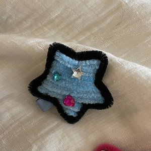 Detail of blue plush star hair clip with colorful rhinestones on a beige cloth
