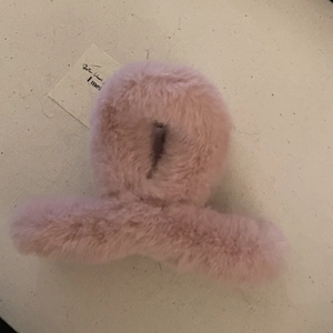 Détail rapproché d'une pince à cheveux en fourrure de lapin rose sur fond en tissu