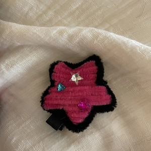 Detailed view of plush star hair clip with pink and black fuzzy texture and rhinestones