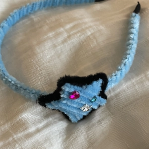 Detailed close-up of blue and black plush hair clip with rhinestone star ornament