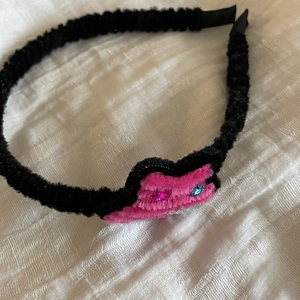Detail of black velvet headband with pink chenille hearts and small sparkling rhinestones