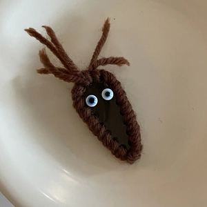Detail of handmade brown knitted hair clip with cute cartoon eyes and antler design
