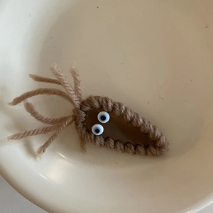 Macro detail of a handmade brown knitted hair clip with blue funny googly eyes decoration