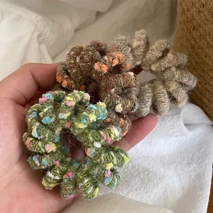 Set of colorful knitted wool covered spiral hair ties held in hand with soft natural lighting