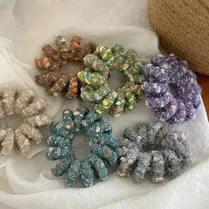 Detailed view of six colorful knitted wool spiral hair ties with thick grainy texture